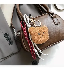 Close-up of cute brown teddy bear plush charm and woven rope accessory on handbag