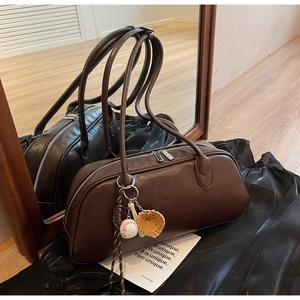 Detail of a dark brown matte leather handbag with baseball charm in mirror reflection