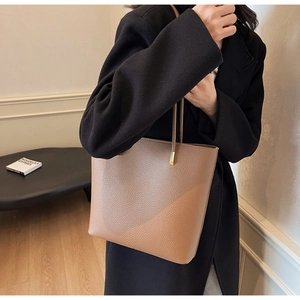 Detail of brown lychee grain leather tote bag with gold metal hardware and long shoulder strap