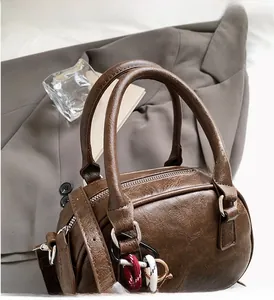 Detailed close-up of dark brown faux leather boston bag with silver hardware and woven cord