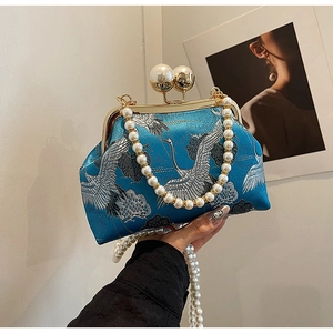 Close-up of peacock blue satin handbag with white crane embroidery and pearl handle
