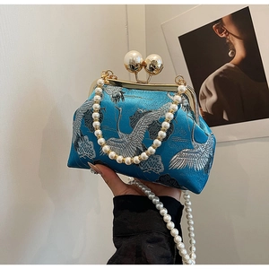 Detail of blue satin purse with silver crane embroidery and pearl clasp handle