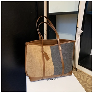 Detail view of large tote bag featuring color-block design and premium leather trim straps