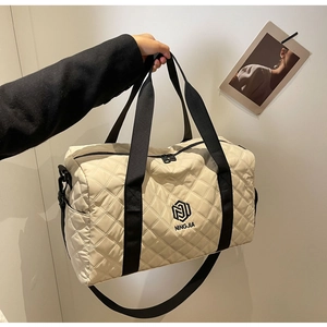Dettaglio della trama in nylon trapuntato e logo ricamato sulla grande borsa da viaggio
