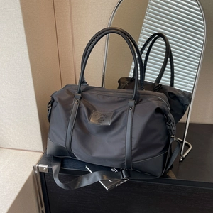 Large black travel duffel bag in durable nylon with leather handles and adjustable strap