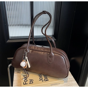 Detail view of dark brown retro baguette bag with unique baseball keychain accessory