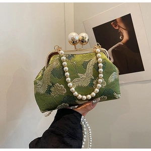 Detail of green satin evening clutch with crane embroidery and pearl clasp handle