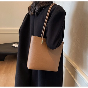 Detail view of the caramel lychee pattern leather and golden metal hardware on tote bag