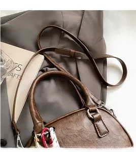 Detail view of brown vintage texture leather handbag with woven rope tassel and slim strap