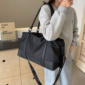 Large black travel duffel bag with crossbody strap and reinforced handles on a model