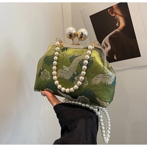 Close-up of crane embroidery on green satin bag with large pearl clasp and bead chain