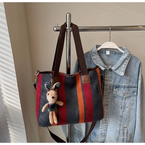 Macro detail of striped canvas tote bag with brown straps and cute rabbit charm pendant