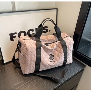 Dettaglio della borsa da viaggio trapuntata rosa con manici neri rinforzati e tasche laterali