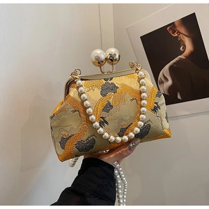 Detail of vintage golden crane embroidery and pearl clasp on an elegant evening bag