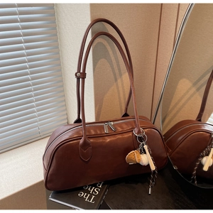 Macro shot of dark brown cylindrical bag with baseball charms and long shoulder straps