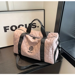 Dettaglio della borsa da viaggio trapuntata rosa chiaro con trama e tracolla nera
