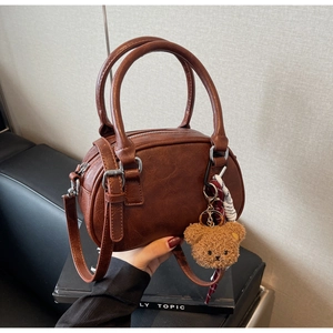Detail of vintage brown leather handbag with plush bear charm and adjustable strap