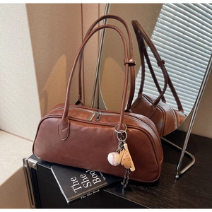 Detail of dark brown matte leather bag with silver double zippers and baseball charm