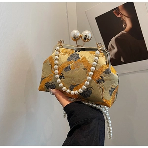 Detail of golden brocade evening bag with crane patterns and pearl clasp closure