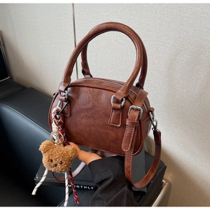 Detail shot of vintage brown Boston bag featuring pebbled texture and plush bear charm