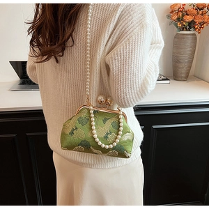 Detail of green silk evening bag with crane embroidery and pearl clasp in life scene