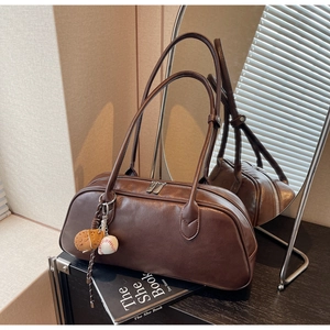 Detail of dark brown faux leather shoulder bag with baseball glove pendant and silver zipper