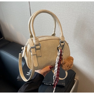 Close-up of beige crossbody bag with lychee texture and cute brown bear charm