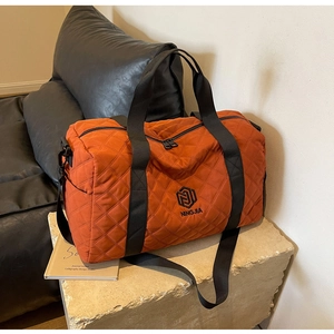 Borsa da viaggio trapuntata arancione caramello con cuciture a rombi e manici