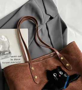 Macro view of brown suede tote bag featuring black cat embroidery and leather handles