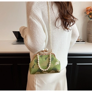 Detailed view of green satin embroidery bag with pearl strap and crane pattern