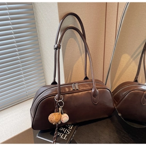 Detailed macro view of retro brown baguette bag with baseball leather charm and silver hardware