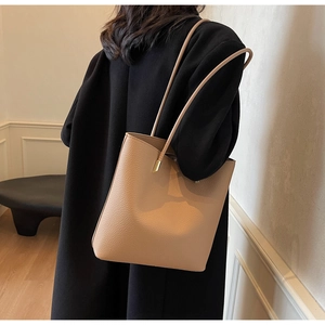 Detail of beige tote bag with litchi texture and gold metal buckle on shoulder strap