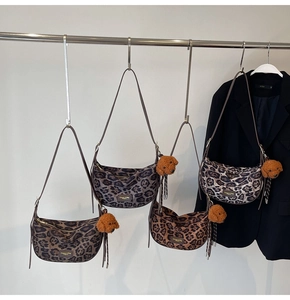 Detail of leopard print crescent bags featuring plush bear charms and zipper texture