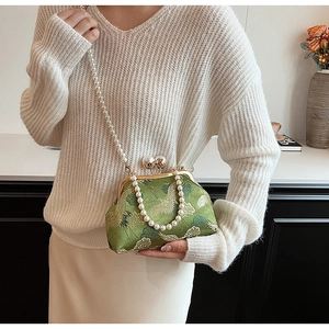 Detailed view of green silk evening bag with crane patterns and large pearl clasp accents