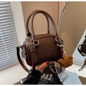 Detailed close-up of brown Boston handbag with cute plush bear charm and plaid ribbon detail