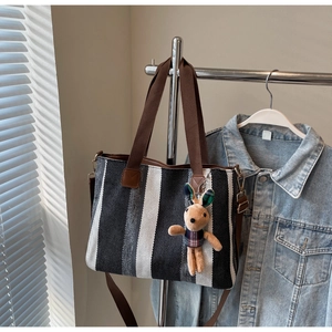 Close-up of striped canvas tote bag with brown straps and cute rabbit plush charm
