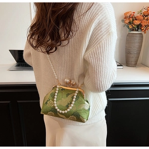 Detail of vintage green embroidery bag with crane patterns and pearl handle shown on model