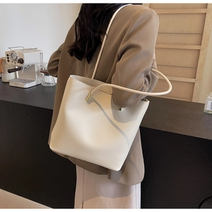 Detail of white pebble leather tote bag with gold metal accents on the shoulder strap