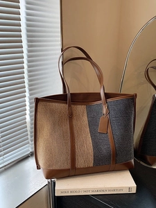 Large two-tone fabric tote bag with brown leather handles on a modern studio background