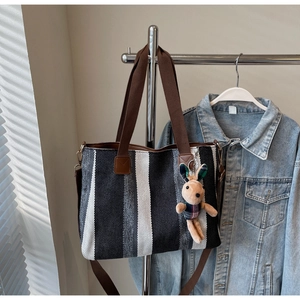 Detailed view of canvas tote with vertical stripes and cute plush rabbit charm accessory