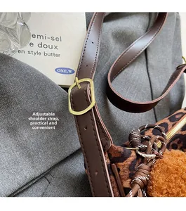Detail of adjustable leather strap with gold buckle on leopard print shoulder bag