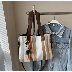 Detail of striped canvas tote bag with woven handles and cute bunny keychain pendant