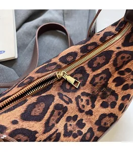 Close-up of leopard print bag featuring premium gold zipper and brown leather strap details