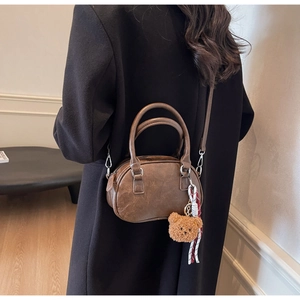 Detailed side view of a vintage brown mini pillow bag styled with a cute bear charm