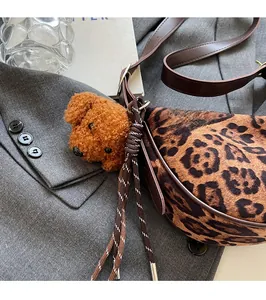 Detail of leopard print moon bag with brown puppy plush charm on a grey suit