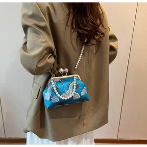 Peacock blue crossbody bag with crane embroidery and pearl strap on model's shoulder