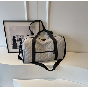 Dettaglio di una grande borsa da viaggio grigia trapuntata con robuste cinghie nere e zip