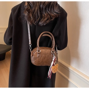 Detail of vintage brown PU leather handbag with decorative woven tassel and pompom