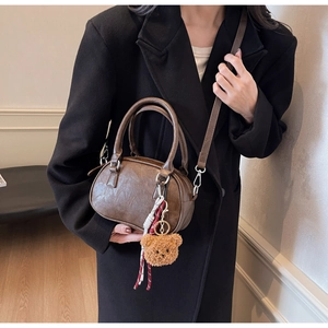 Detailed macro view of vintage brown leather texture and cute bear pendant on a handbag