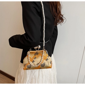 Detailed view of embroidery crane bag with pearl handle and metallic frame clasp